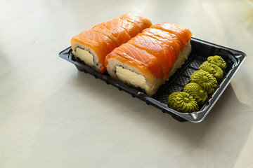 Tasty sushi rolls with salmon and cream cheese on light background