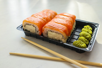 Tasty sushi rolls with salmon and cream cheese on light background