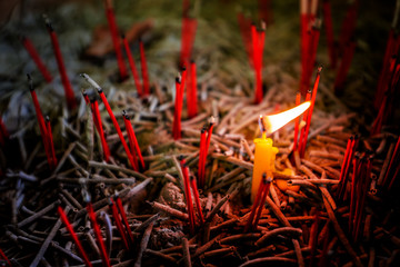 Glowing candle light in the middle of blur burned red incense,  praying and wishing concept