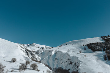 A snowy winter landscape in the mountains under a bright blue sky