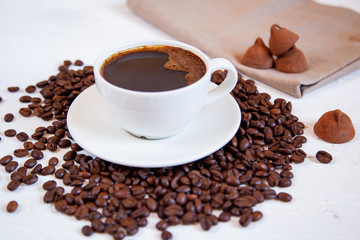 White cup of coffee stands on coffee beans