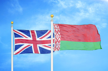 United Kingdom and Belarus two flags on flagpoles and blue cloudy sky