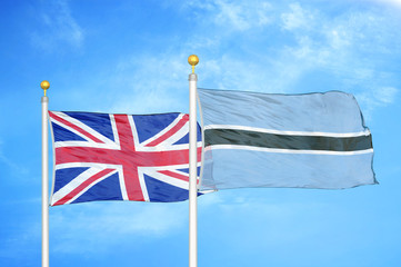 United Kingdom and Botswana two flags on flagpoles and blue cloudy sky