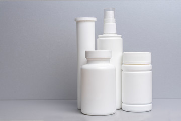 4 plastic containers for medicines and vitamins, a bottle with a spray bottle on a gray background....