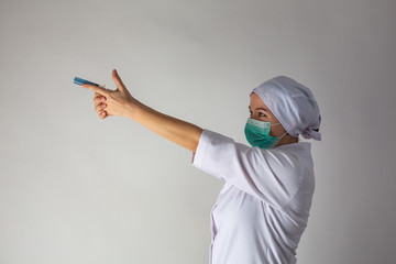 The girl in a medical coat holds a large syringe with blue liquid like a gun