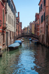 View of narrow Canal with boats and gondolas in Venice, Italy