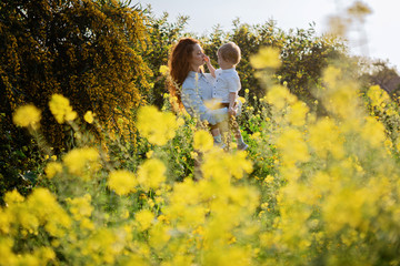 Mother and child enjoy early spring in blooming yellow flowers field or garden eco friendly in...
