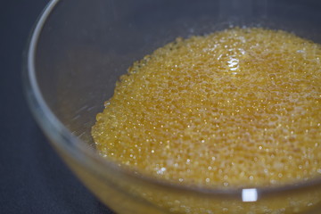 Fresh pike caviar in a transparent glass plate on a black background.