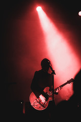 Obraz na płótnie Canvas Silhouette of a man playing the guitar on stage. Dark background, smoke, spotlights