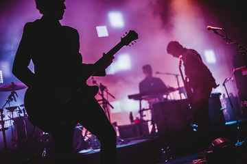 Blurred background light on rock concert with silhouette of musicians - obrazy, fototapety, plakaty