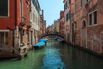 View of narrow Canal with boats and gondolas in Venice, Italy
