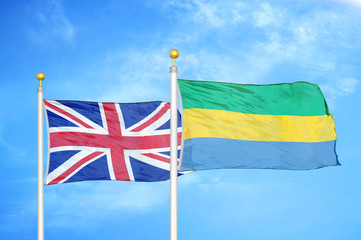 United Kingdom and Gabon two flags on flagpoles and blue cloudy sky
