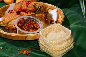 Fried chicken and roasted chili paste serve with glutinous rice in a bamboo tray.