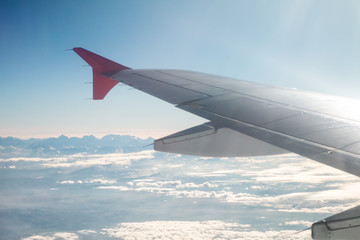Passenger airplane flying above the mountain peaks. Wing view