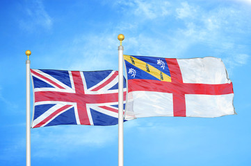 United Kingdom and Herm two flags on flagpoles and blue cloudy sky