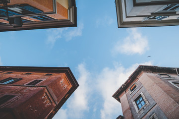 Fototapeta na wymiar Sky between old buildings walls from below in Rome, Italy