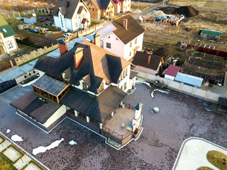 Aerial top view of new residential house cottage with shingle roof on fenced big yard on sunny day.