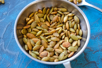 Pumpkin seeds, toasted pumpkin seeds, in Minsk on a dark blue table.