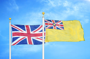 United Kingdom and Niue two flags on flagpoles and blue cloudy sky