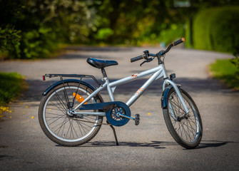 Fototapeta na wymiar Grey and black children's bike standing on a road.