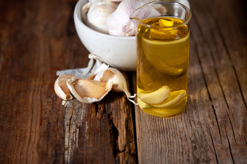 Garlic oil and garlic on a wooden table.