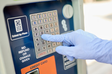 The right hand in the blue glove on the dial on the parking meter