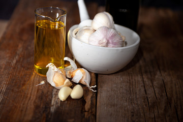 Garlic oil and garlic on a wooden table.