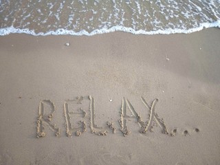 Title Relax... on a sandy beach with a sea wave above. Vacation concept.