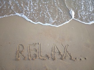 Fototapeta premium Title Relax... on a sandy beach with a sea wave above. Vacation concept. 