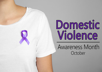 Woman with purple ribbon on grey background, closeup. Symbol of Domestic Violence Awareness