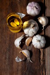 Garlic oil and garlic on a wooden table.