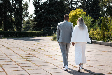 The bride and groom walk in the park on the wedding day