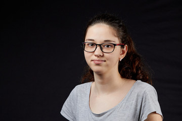 Fototapeta premium portrait of a shy young girl with glasses on the dark background