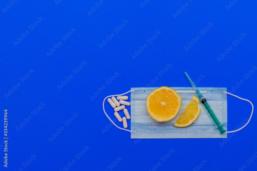 Wall mural medical concept. face mask, syringe, jar for medicines and pills on a blue background. flat lay, cop