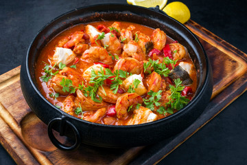 Traditional American fish stew cioppino with prawns, and fish as top view in a modern design...