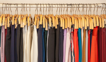 Clothes hang on a shelf in clothes store. Clothes for women hanging on hangers in home closet or shopping mall for store sale concept.
