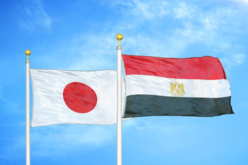 Japan and Egypt two flags on flagpoles and blue cloudy sky