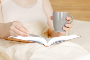 woman lying down on bed reading a book at home, self-isolation