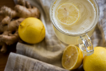 Obraz na płótnie Canvas Lemon ginger drink in dark light with a soft cloth and texture
