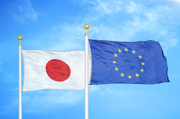 Japan and European Union two flags on flagpoles and blue cloudy sky
