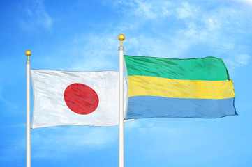 Japan and Gabon two flags on flagpoles and blue cloudy sky