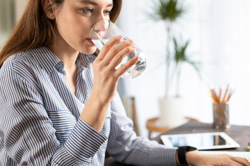 Freelancer young woman working at home and drinking water