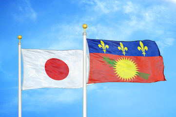 Japan and Guadeloupe two flags on flagpoles and blue cloudy sky
