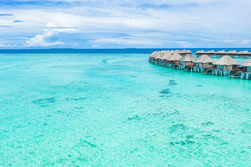 Naklejka na ściany i meble Luxury overwater villas in blue lagoon and deep blue sea from aerial view in Maldives or at Bora Bora island, Tahiti, French Polynesia