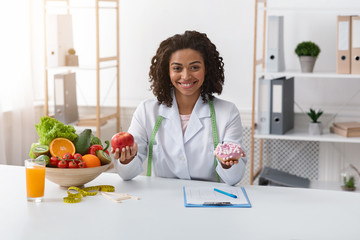 Pretty woman dietary doctor holding donut and apple