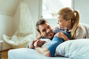 Young happy couple having fun while talking in bedroom.