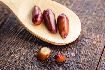 pine nut seed seen from above, shelled and cooked, ready to be used as a condiment. Rustic wooden spoon, healthy cuisine.