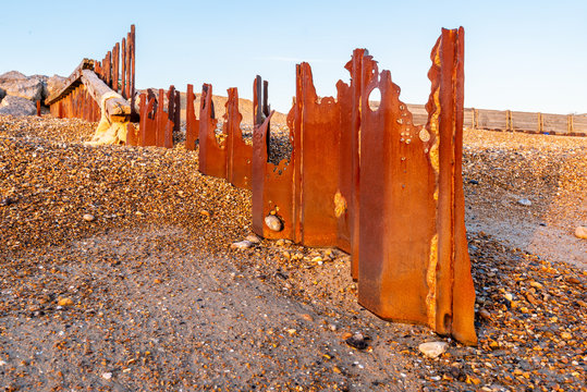 Rotten iron structure forming part of sea defences on a shingle beach