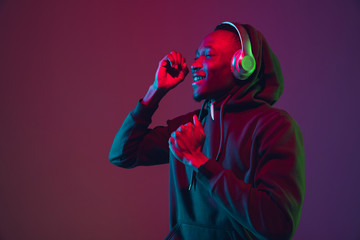 African-american man's portrait with headphones on gradient studio background in neon light....