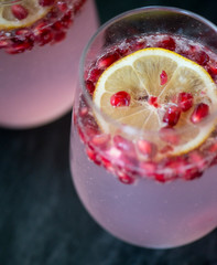 pomegranates in a lemon drink with sparkling water in a wine glass